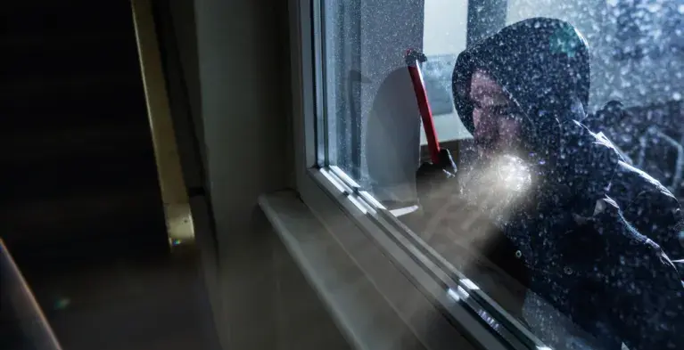 Inbreker kijkt door het raam naar binnen