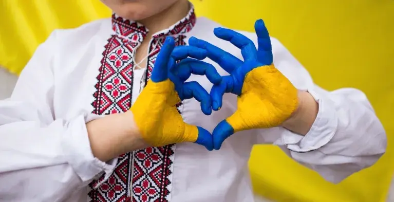 Persoon vormt hartje met handen geverfd in kleuren van Oekraïnse vlag