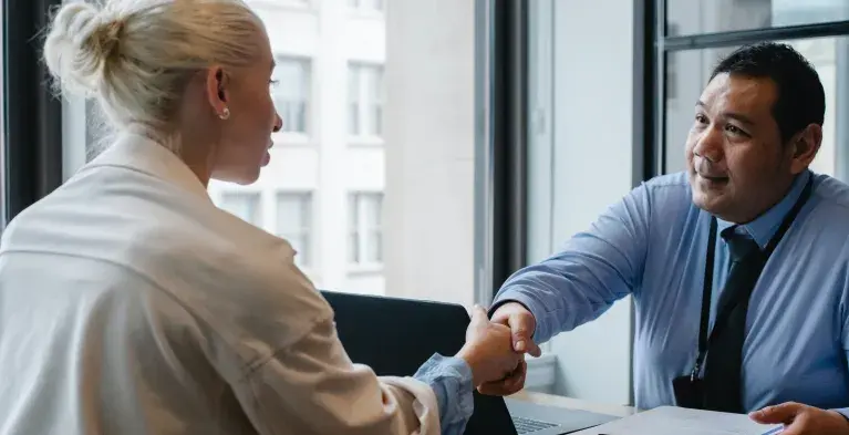 Twee mensen schudden elkaar de hand op sollicitatiegesprek