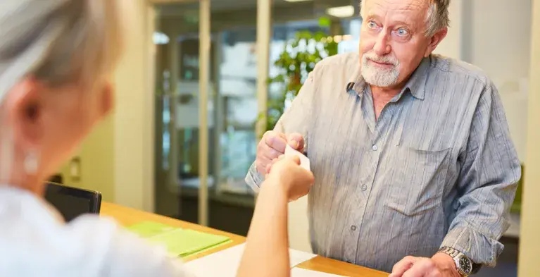 man bij balie pakt visitekaartje aan