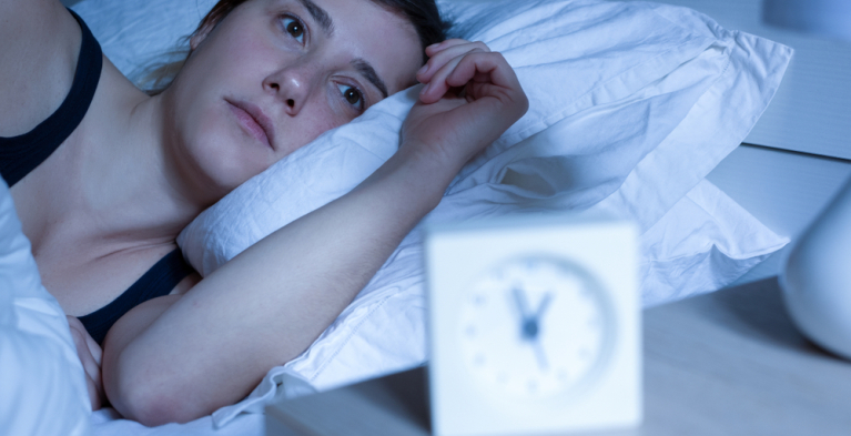 Vrouw ligt wakker te piekeren in bed