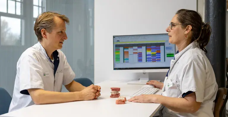 Orthodontist in gesprek met gebitsmodel op tafel