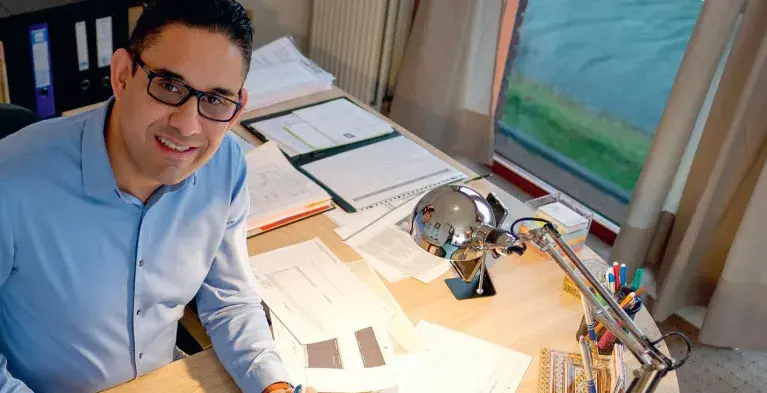 Tandarts Sepand Manouchehr achter zijn bureau na de verbouwing van zijn nieuwe praktijk