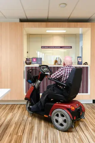 Persoon in een rolstoel rijdt naar de balie
