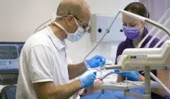 Behandeling bij de tandarts met assistent aan de stoel