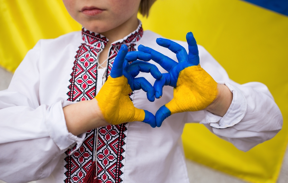 Persoon vormt hartje met handen geverfd in kleuren van Oekraïnse vlag