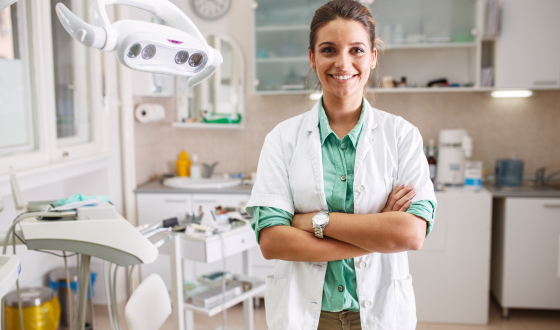 Vrouwelijke tandarts kijkt tevreden in de camera