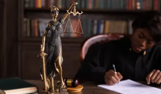 Rechter zit achter tafel met beeld van vrouwe Justitia