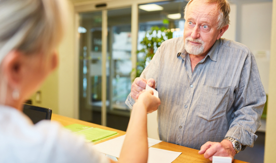 man bij balie pakt visitekaartje aan