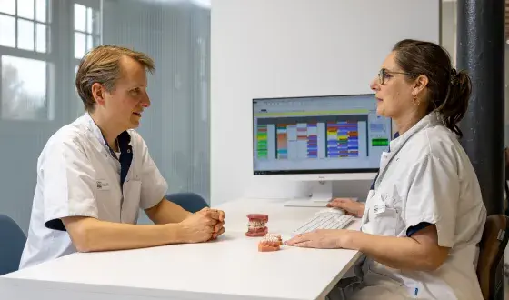 Orthodontist in gesprek met gebitsmodel op tafel