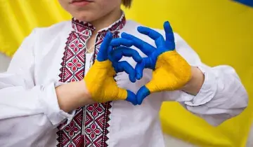 Persoon vormt hartje met handen geverfd in kleuren van Oekraïnse vlag