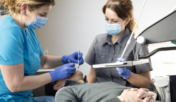 Behandeling bij de tandarts aan de stoel met assistent ernaast