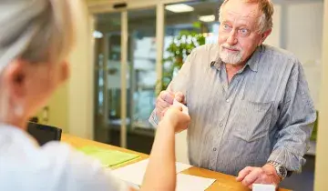 man bij balie pakt visitekaartje aan
