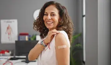 Een vrouw toont een pleister op haar bovenarm
